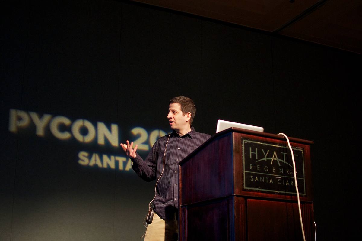 Přednášející u plátna s ukázkou zdrojového kódu na konferenci PyCon