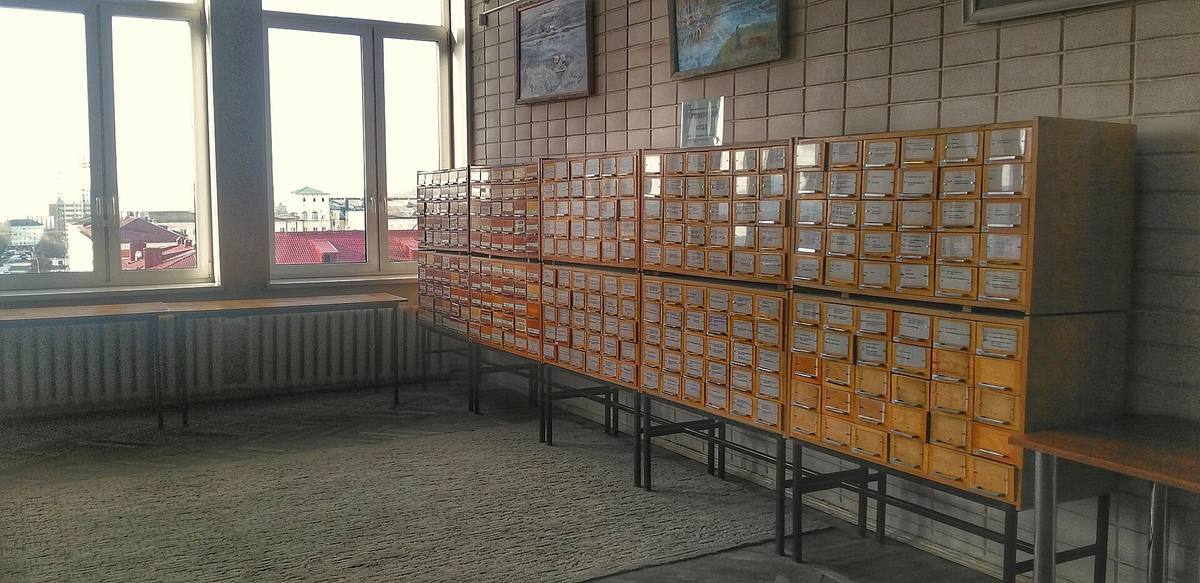 Řada dřevěných katalogových skříní s vytaženými zásuvkami lístků v knihovně