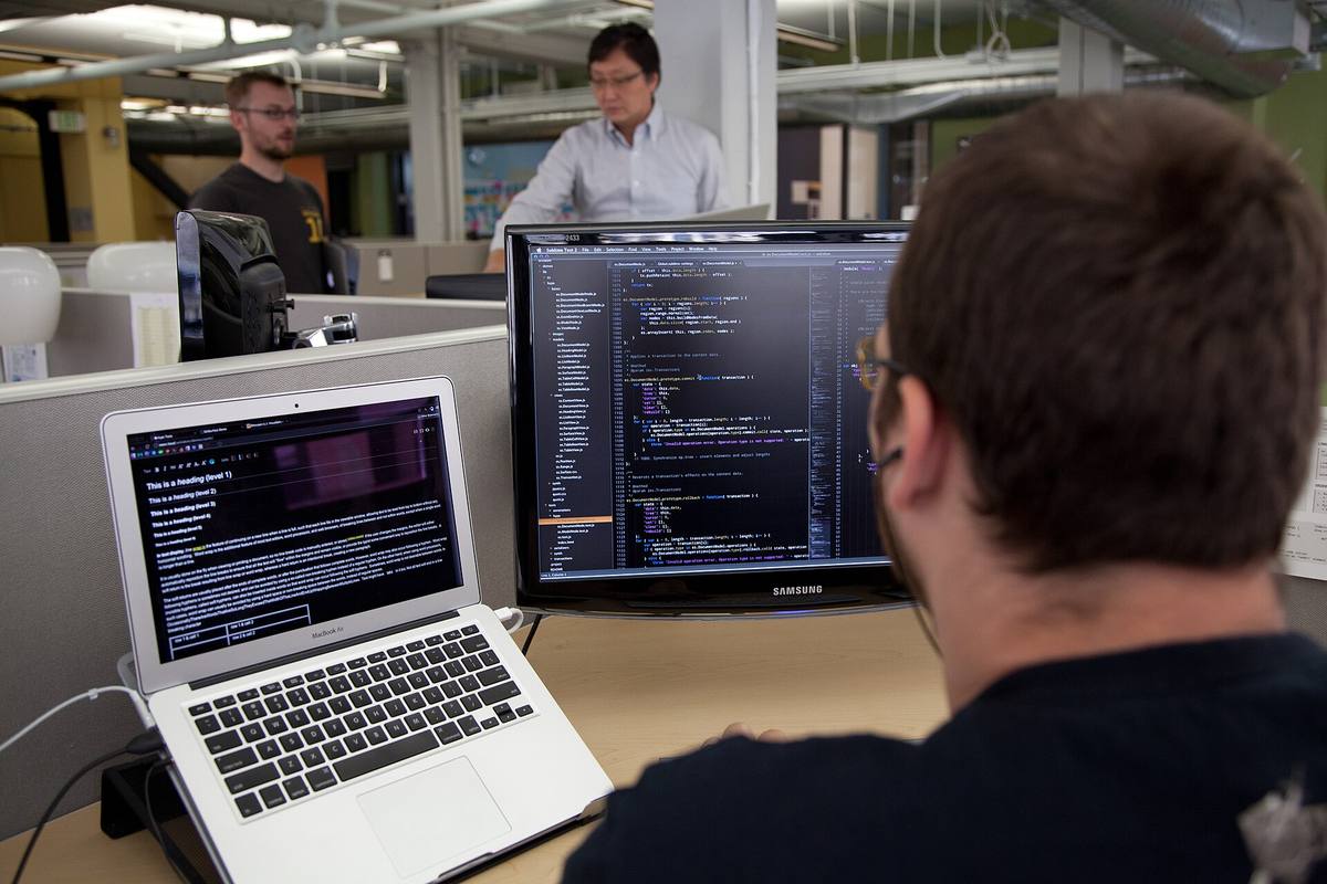 Programátor před monitorem se zdrojovým kódem
