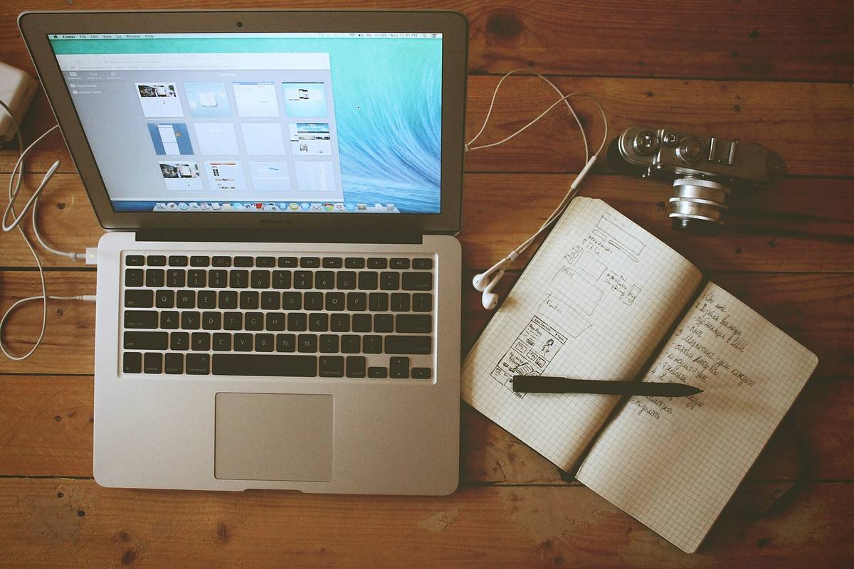 Notebook, otevřený zápisník a fotoaparát na dřevěném stole