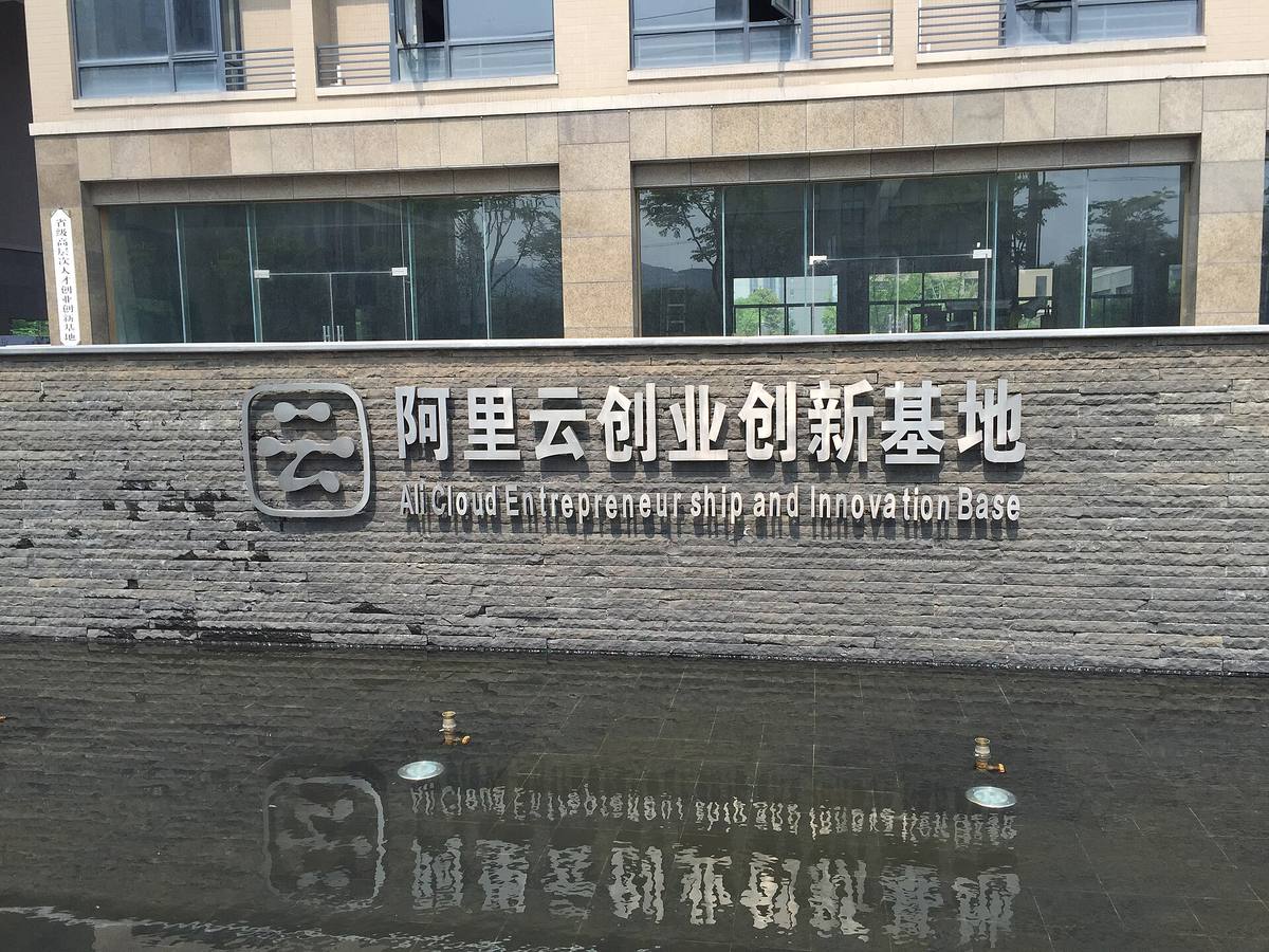 Nápis podnikatelského centra Alibaba Cloud na kamenné zdi nad vodní plochou
