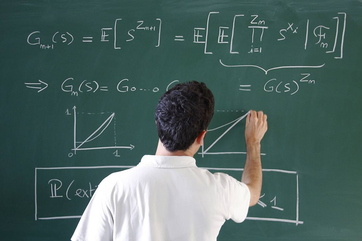 Matematik píše vzorce a graf na zelenou tabuli