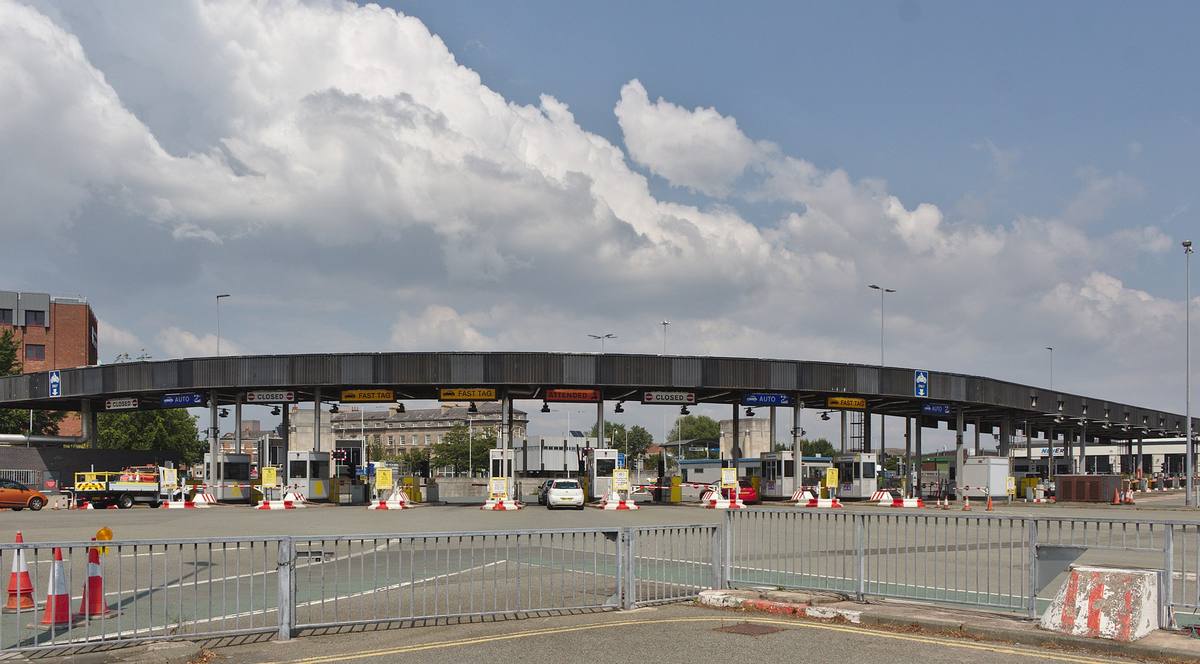 Řada mýtných bran s nápisy Closed, Auto, Fast Tag a Attended nad jízdními pruhy
