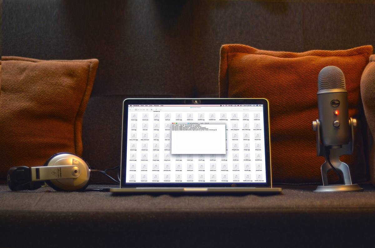 Notebook mezi studiovým mikrofonem a sluchátky na pohovce