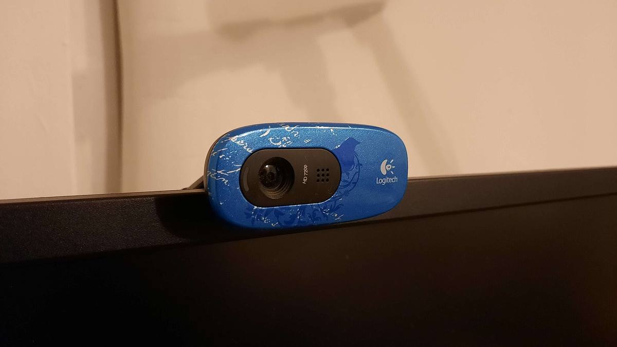 Modrá webkamera Logitech na horní hraně monitoru