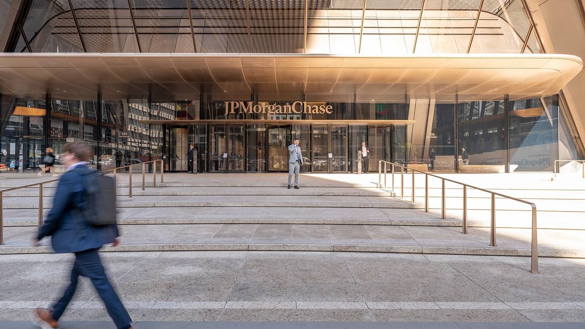 Prosklený vchod se schodištěm a nápisem JPMorgan Chase, kolem jdou lidé